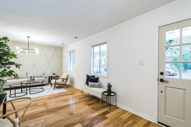 foyer entrance featuring a healthy amount of sunlight, wood-type flooring, and a chandelier