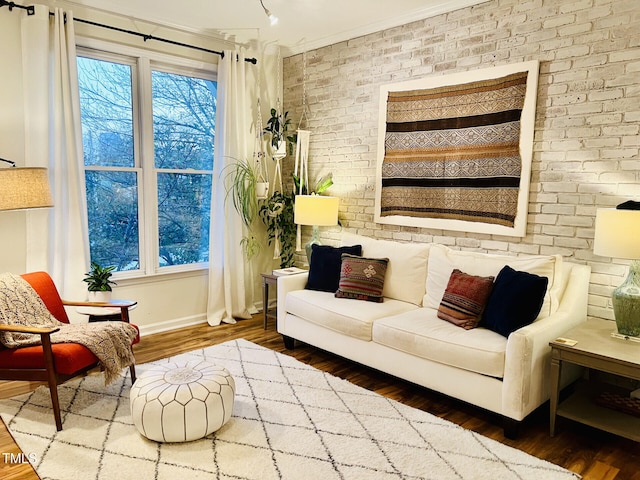 sitting room with ornamental molding, brick wall, and hardwood / wood-style flooring