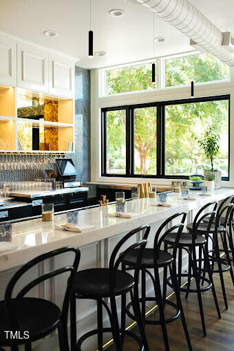 bar featuring dark hardwood / wood-style floors, light stone counters, and white cabinetry