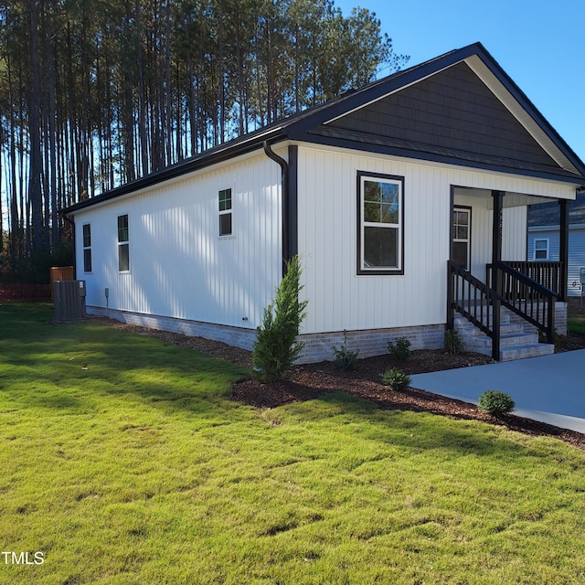 view of front of home with central AC, a front lawn, and covered porch