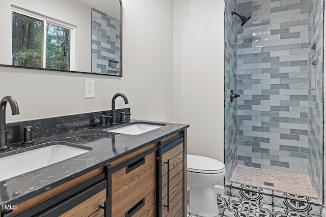 bathroom with tiled shower, tile patterned flooring, vanity, and toilet