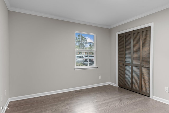 unfurnished bedroom featuring a closet, crown molding, and light hardwood / wood-style flooring