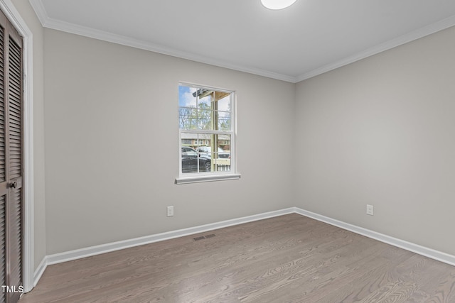 unfurnished bedroom with light wood-type flooring, crown molding, and a closet