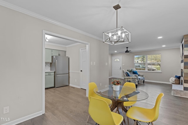 dining room with ceiling fan with notable chandelier, hardwood / wood-style flooring, and crown molding