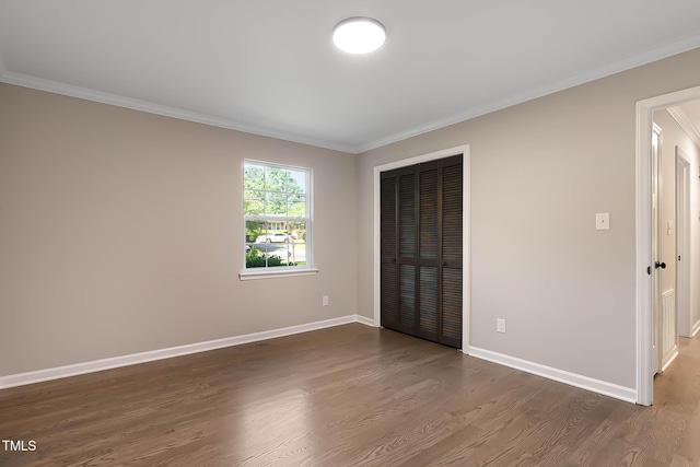 2704 Ross Rd, Durham, NC 27703 - unfurnished bedroom featuring crown molding, dark wood-type flooring, a closet, and baseboards