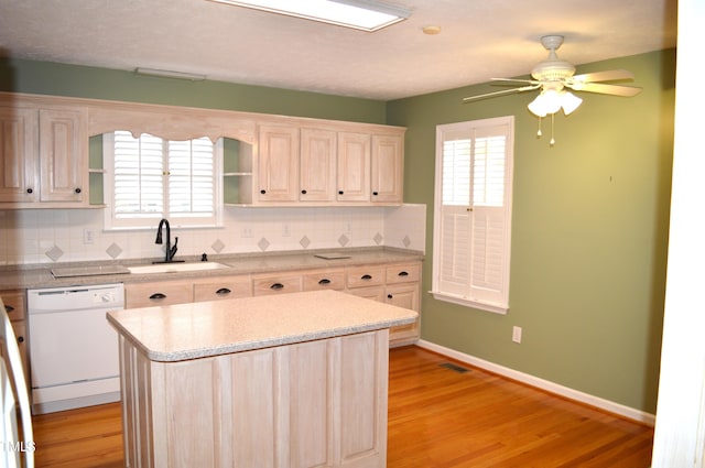 kitchen with dishwasher, sink, light hardwood / wood-style flooring, decorative backsplash, and a kitchen island