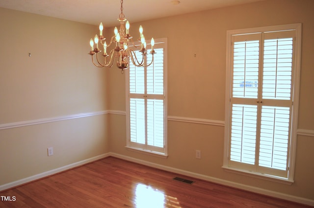 unfurnished room featuring hardwood / wood-style floors and a chandelier