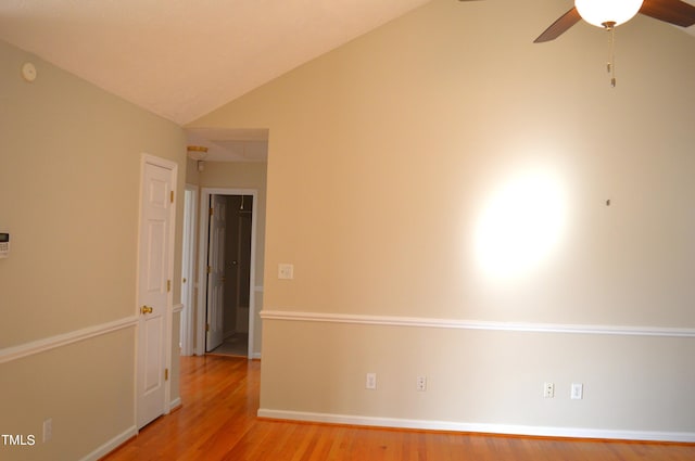 empty room with ceiling fan, light wood-type flooring, and vaulted ceiling