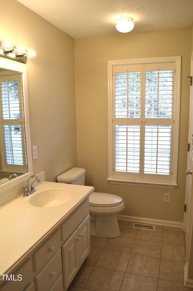 bathroom featuring tile patterned floors, vanity, a textured ceiling, and toilet