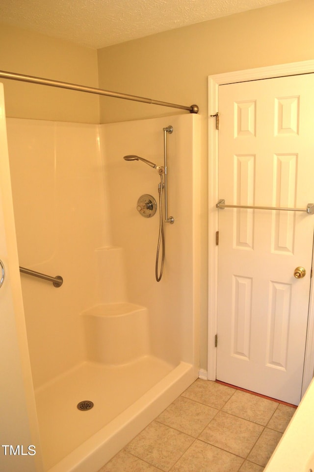 bathroom with a shower, a textured ceiling, and tile patterned floors