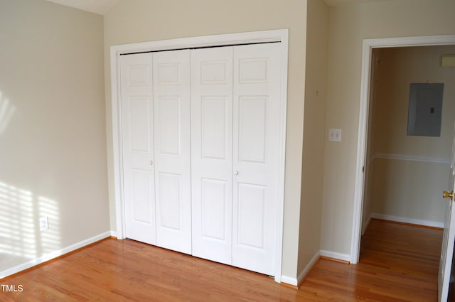 unfurnished bedroom featuring electric panel, a closet, and hardwood / wood-style flooring