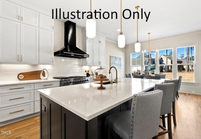 kitchen with sink, an island with sink, white cabinetry, and wall chimney range hood