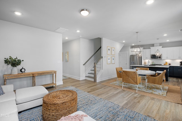 living room with light hardwood / wood-style floors, sink, and a chandelier