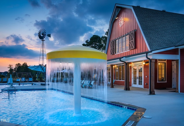 pool at dusk featuring a patio