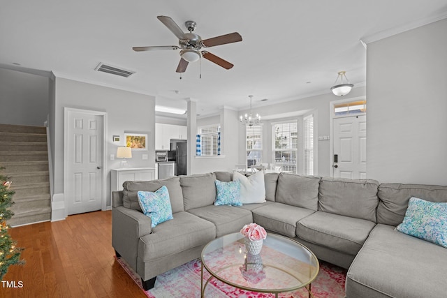 living room with ceiling fan with notable chandelier, light hardwood / wood-style flooring, and crown molding