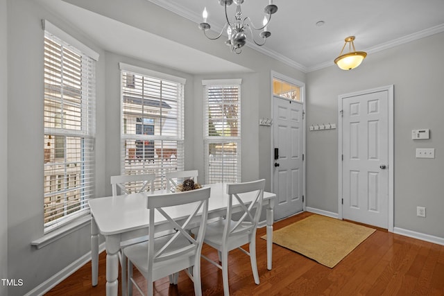 dining area with hardwood / wood-style flooring, crown molding, and a notable chandelier