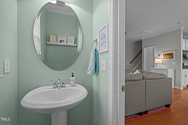 bathroom featuring wood-type flooring, ornamental molding, and sink