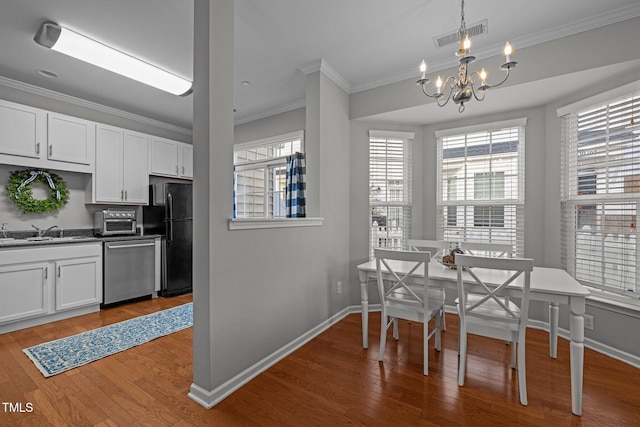 dining space featuring crown molding, sink, a chandelier, and hardwood / wood-style flooring