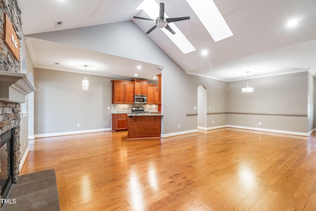 unfurnished living room featuring a skylight, ornamental molding, a fireplace, and light hardwood / wood-style flooring