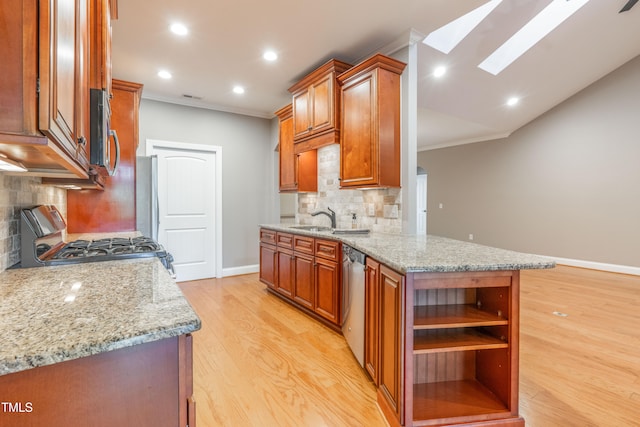 kitchen with a skylight, light stone countertops, stainless steel appliances, tasteful backsplash, and light wood-type flooring