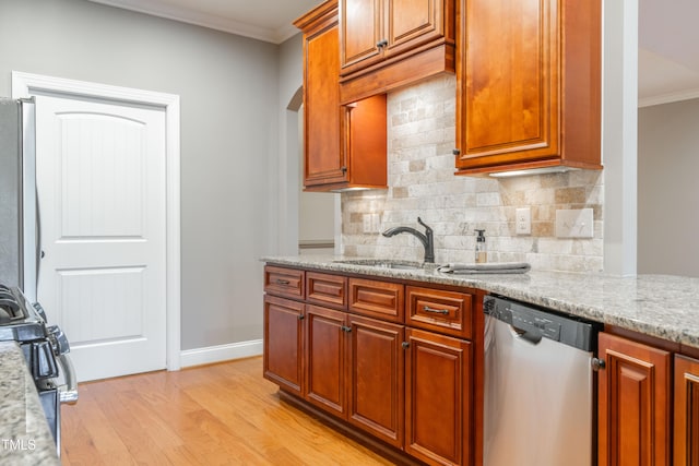 kitchen with light stone countertops, appliances with stainless steel finishes, decorative backsplash, ornamental molding, and light hardwood / wood-style floors