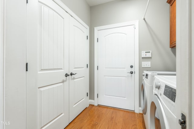 washroom featuring separate washer and dryer, light hardwood / wood-style floors, and cabinets