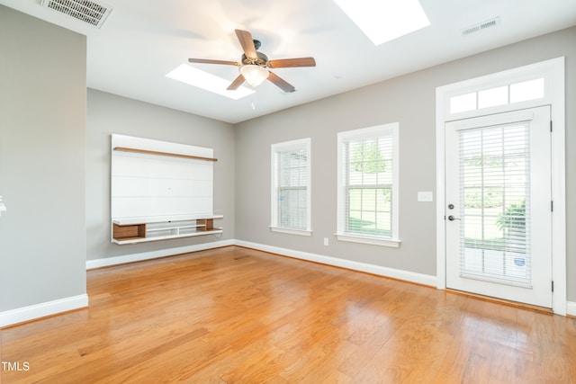 unfurnished room featuring ceiling fan, light hardwood / wood-style floors, and a skylight