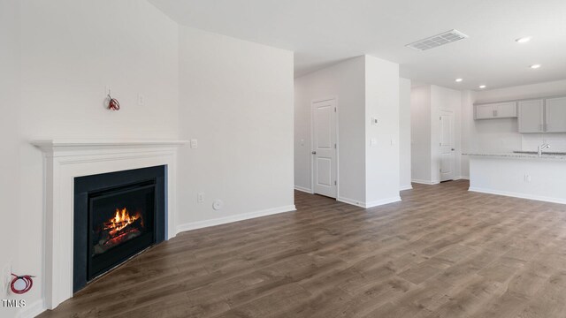 unfurnished living room with dark hardwood / wood-style flooring and sink