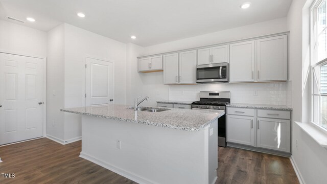 kitchen with an island with sink, stainless steel appliances, a healthy amount of sunlight, and sink