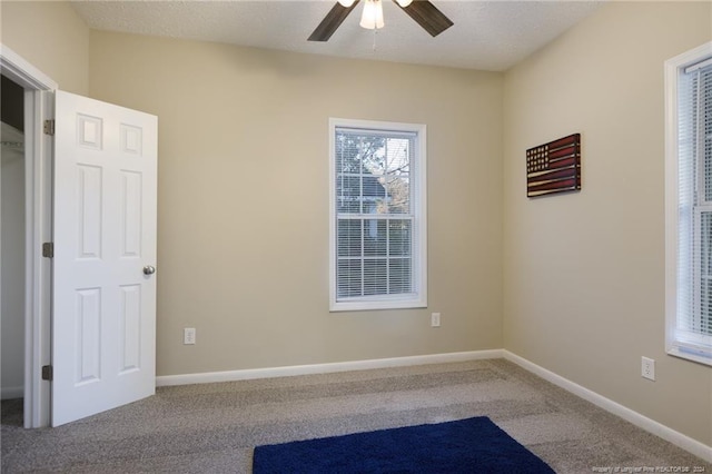 carpeted spare room featuring a textured ceiling and ceiling fan