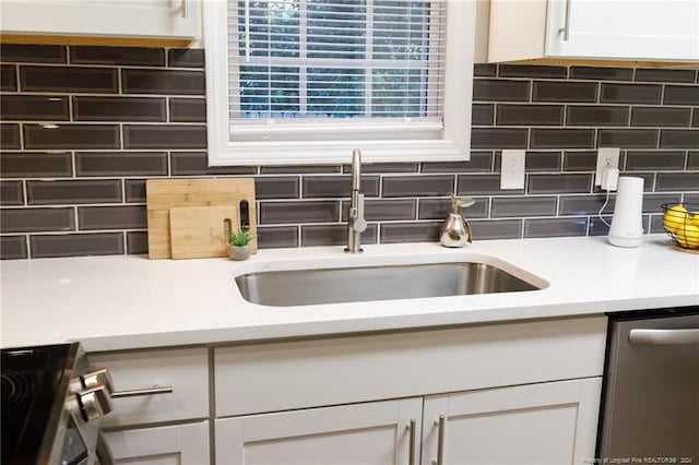 kitchen with dishwasher, decorative backsplash, white cabinetry, and sink