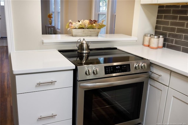 kitchen featuring tasteful backsplash, electric stove, white cabinetry, and kitchen peninsula