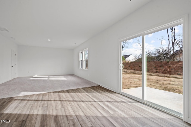 spare room with plenty of natural light and light hardwood / wood-style flooring