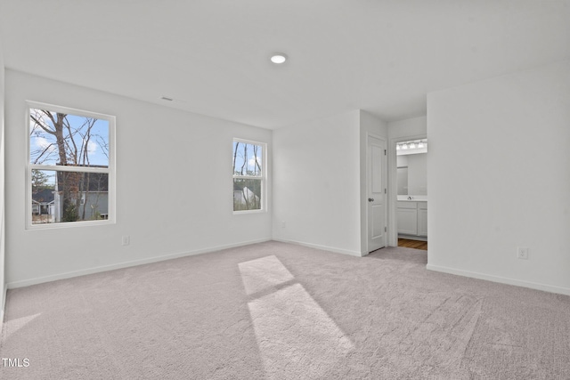 unfurnished bedroom featuring ensuite bathroom and light colored carpet