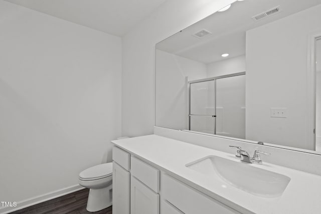 bathroom with wood-type flooring, vanity, toilet, and a shower with door