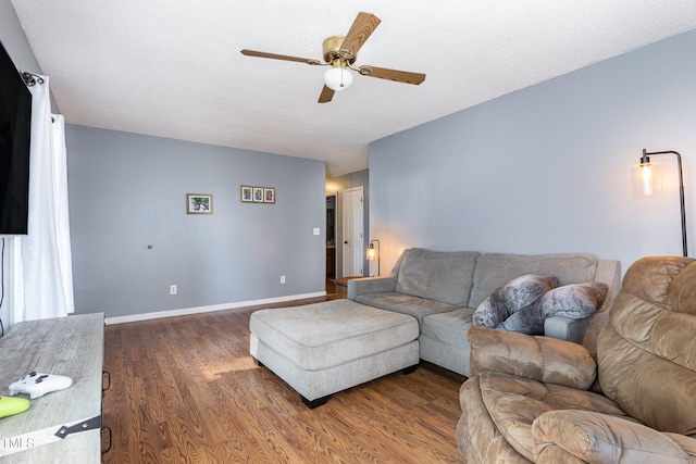 living room with ceiling fan, dark hardwood / wood-style flooring, and a textured ceiling