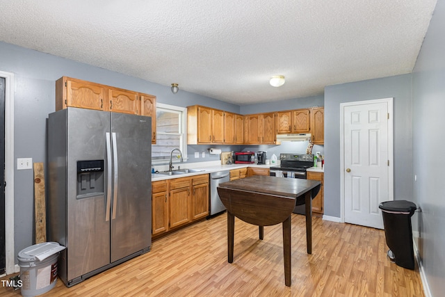 kitchen with a textured ceiling, stainless steel appliances, light hardwood / wood-style flooring, and sink