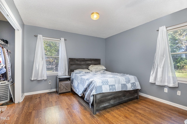 bedroom featuring a textured ceiling, multiple windows, and dark wood-type flooring