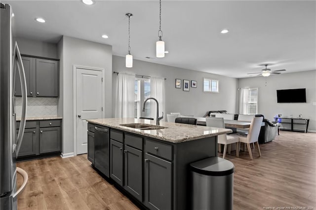 kitchen featuring stainless steel refrigerator, ceiling fan, sink, black dishwasher, and an island with sink