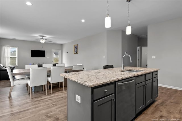 kitchen with sink, an island with sink, hardwood / wood-style floors, and decorative light fixtures