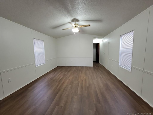 spare room with a textured ceiling, ceiling fan, dark wood-type flooring, and vaulted ceiling