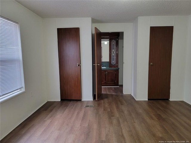 unfurnished bedroom with a textured ceiling and dark wood-type flooring