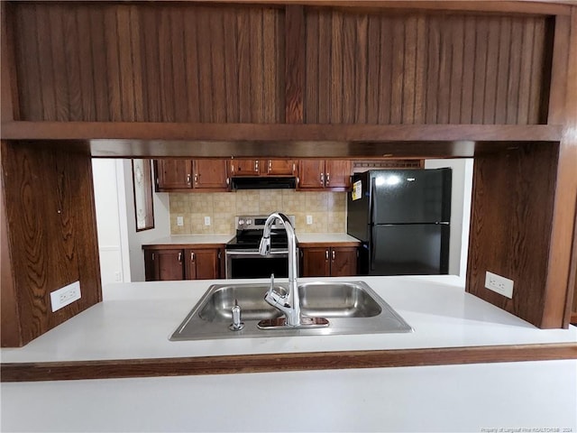 kitchen featuring decorative backsplash, sink, black fridge, and stainless steel electric range