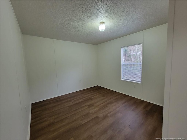 unfurnished room featuring dark hardwood / wood-style flooring and a textured ceiling