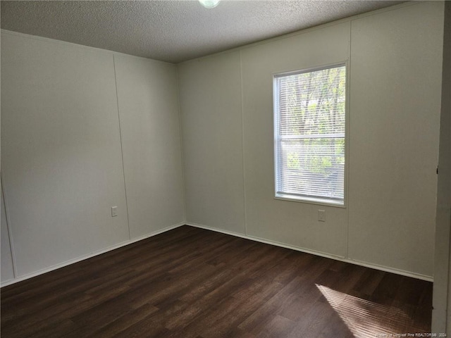 spare room featuring a textured ceiling and dark hardwood / wood-style flooring