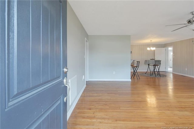 empty room with ceiling fan with notable chandelier and light hardwood / wood-style flooring