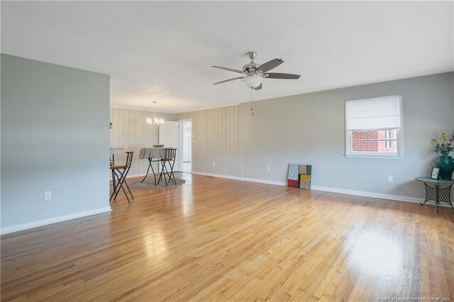 unfurnished room featuring ceiling fan with notable chandelier and light wood-type flooring