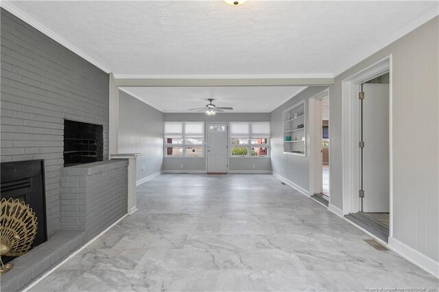 unfurnished living room featuring crown molding, a brick fireplace, ceiling fan, built in shelves, and a textured ceiling