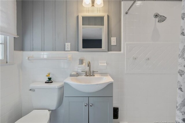 bathroom featuring curtained shower, vanity, tile walls, and toilet