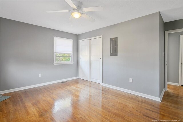 unfurnished bedroom with ceiling fan, a closet, electric panel, and light hardwood / wood-style flooring